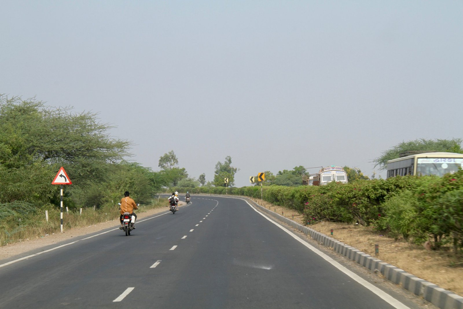 Four-lane highway in Gujarat with motorcycles and road signs