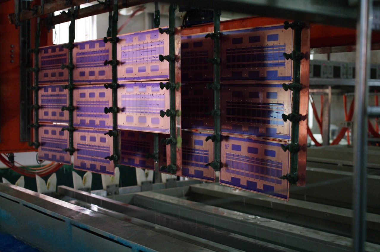Printed circuit boards hanging in a computer-controlled copper electroplating machine